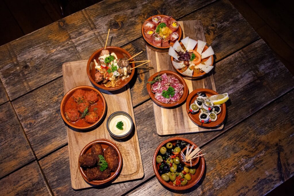 An inviting flat lay of diverse gourmet tapas on a wooden table, perfect for a rustic dining experience.